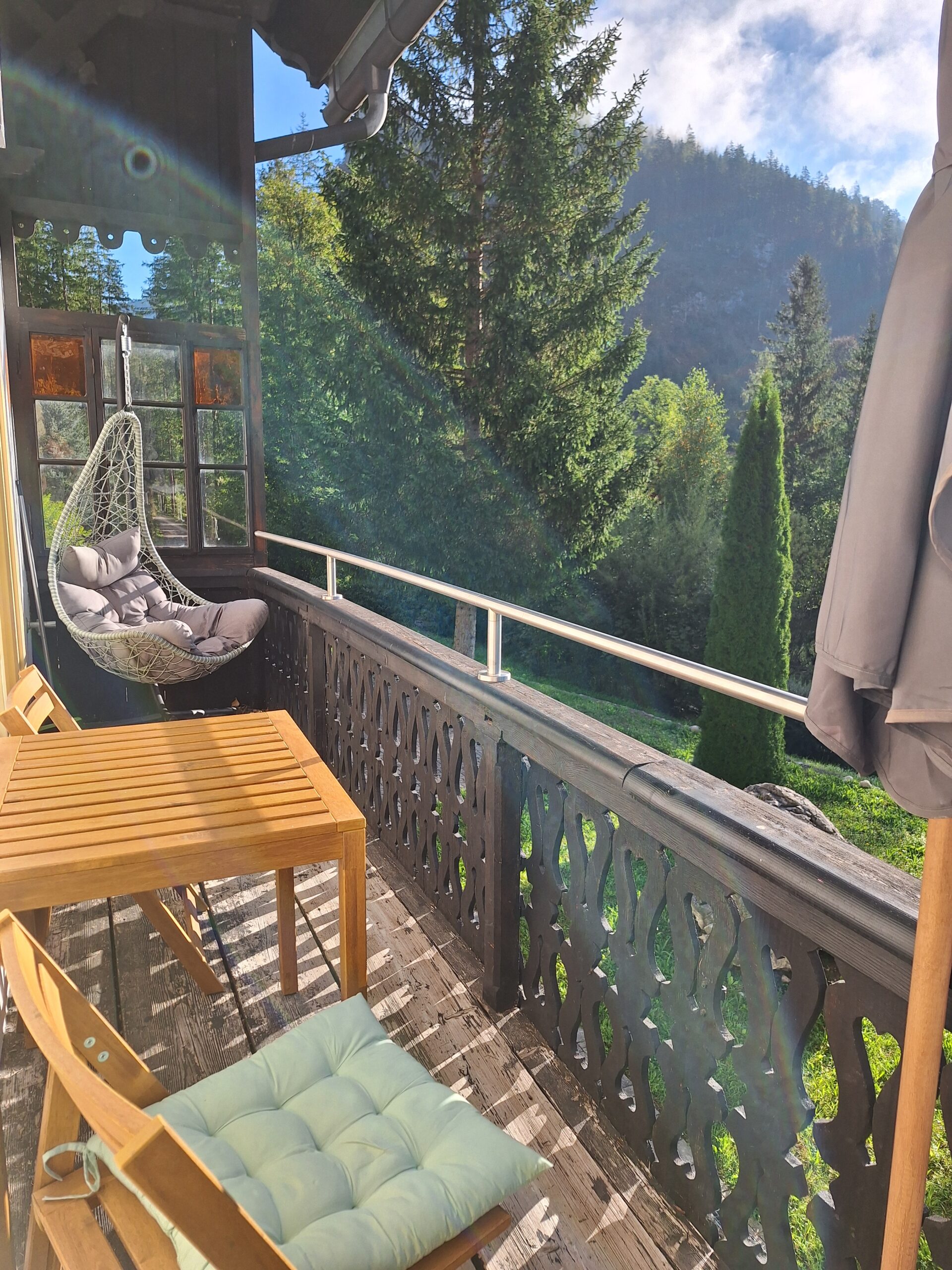 gemütlicher Hängesessel und Tisch mit Stühlen auf dem Balkon